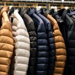 Різноманітні моделі чоловічих пуховиків на вішаках у магазині